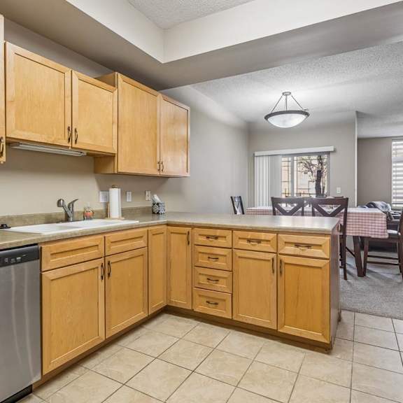 Thumbnail 14 of 29 Open apartment kitchen with light wood cabinets, tile flooring, ample counter space, and adjacent dining area.