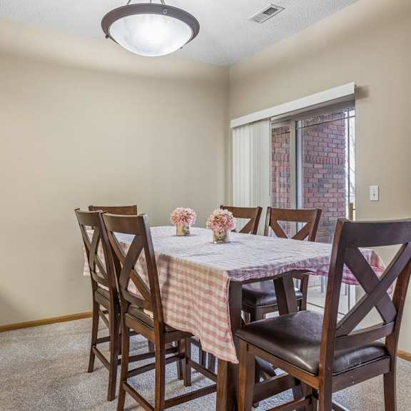 Thumbnail 7 of 29 Dining area in an apartment home with table seating, neutral walls, and sliding glass door access nearby.