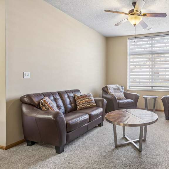 Thumbnail 5 of 29 Spacious apartment living room with plush carpet, large window, fireplace, and open sightlines to the dining area.