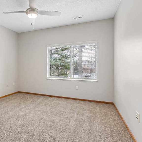 Thumbnail 12 of 18 Carpeted bedroom with ceiling fan and window.