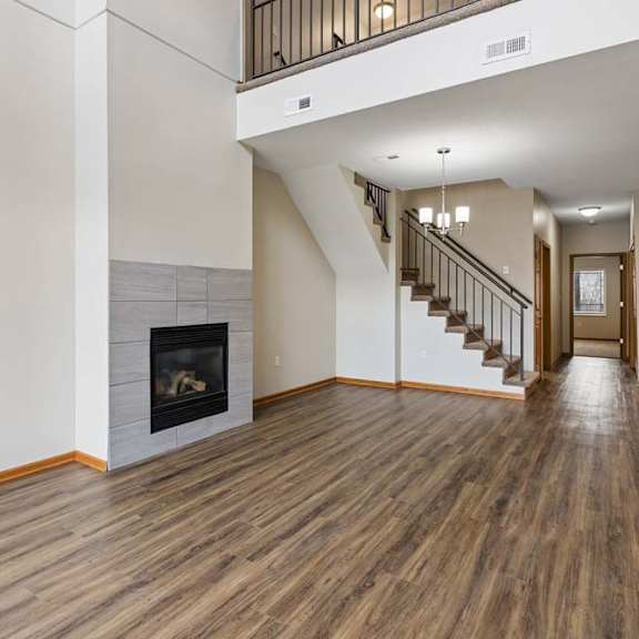 Thumbnail 2 of 18 Spacious living area featuring a fireplace, open staircase, and wood flooring.