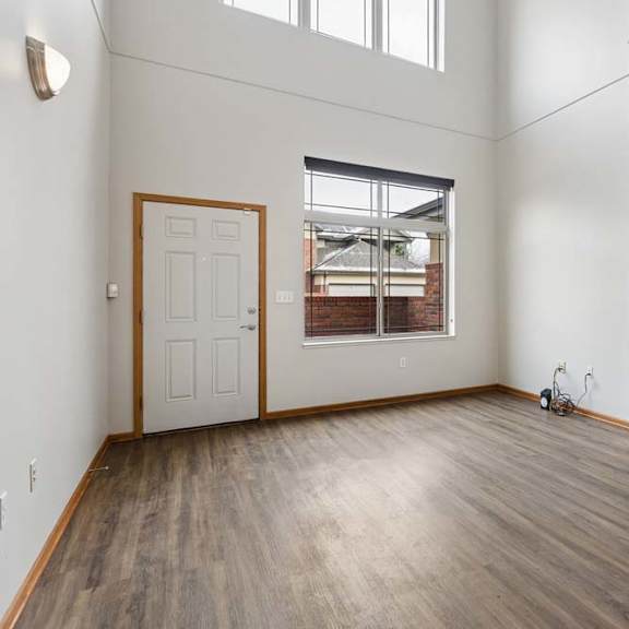 Thumbnail 3 of 18 Open living room with gas fireplace, vaulted ceiling, and wood-style flooring.