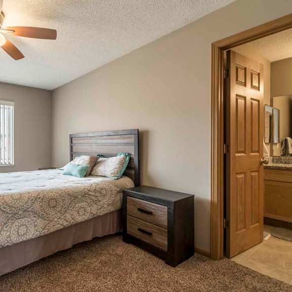 Thumbnail 10 of 21 Master bedroom with attached bathroom and ceiling fan at Southwind Villas in southwest Omaha in La Vista, NE, 68128