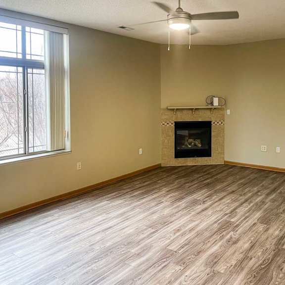 Thumbnail 4 of 18 a living room with a corner fireplace, luxury vinyl tile flooring, and a ceiling fan