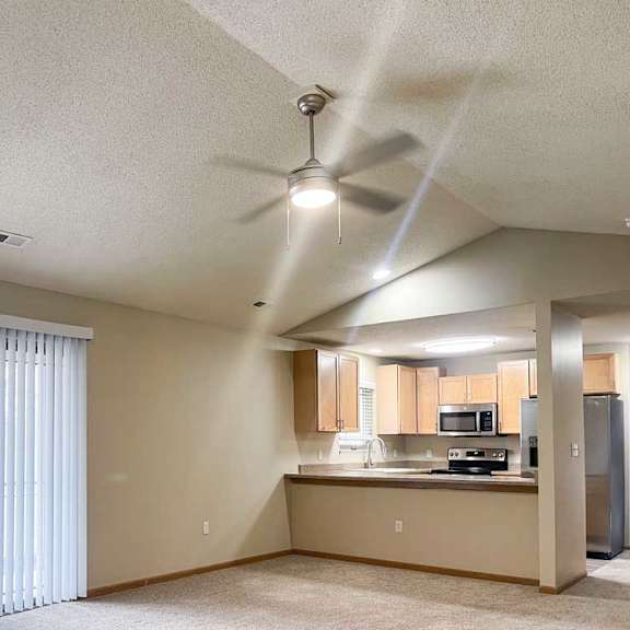 Thumbnail 4 of 21 a living room with a sliding glass door to a balcony in front of a kitchen area