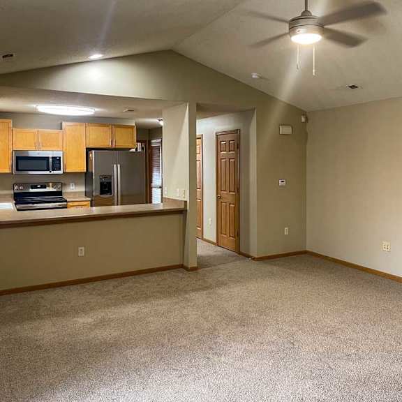 Thumbnail 9 of 21 a living room with a fireplace and a kitchen area in the background