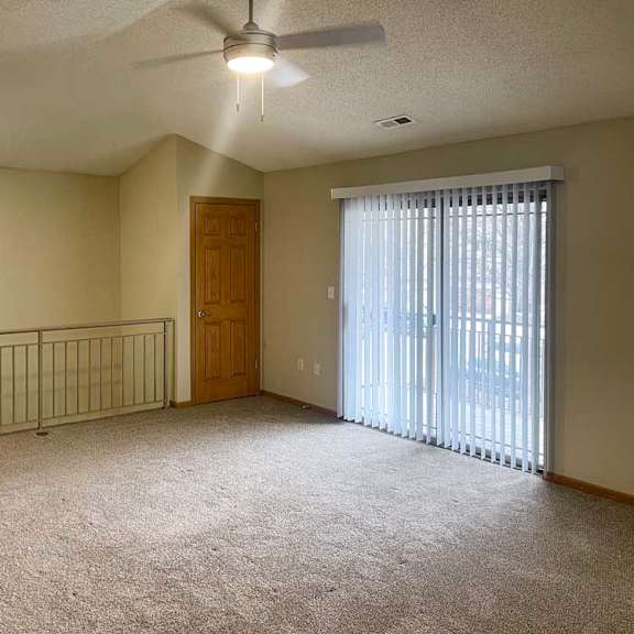 Thumbnail 7 of 21 a spacious living room with a ceiling fan, a coat closet, and a sliding glass door to a balcony