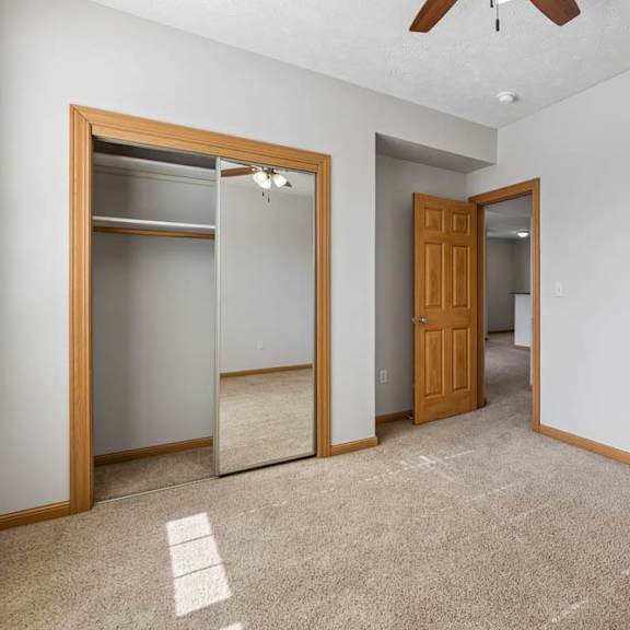 Thumbnail 19 of 19 Bedroom interior highlighting a mirrored sliding-door closet with built-in shelf and hanging rod, plus warm wood trim.
