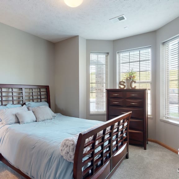 Thumbnail 9 of 19 a bedroom with a bed and a dresser brightened with natural light from windows