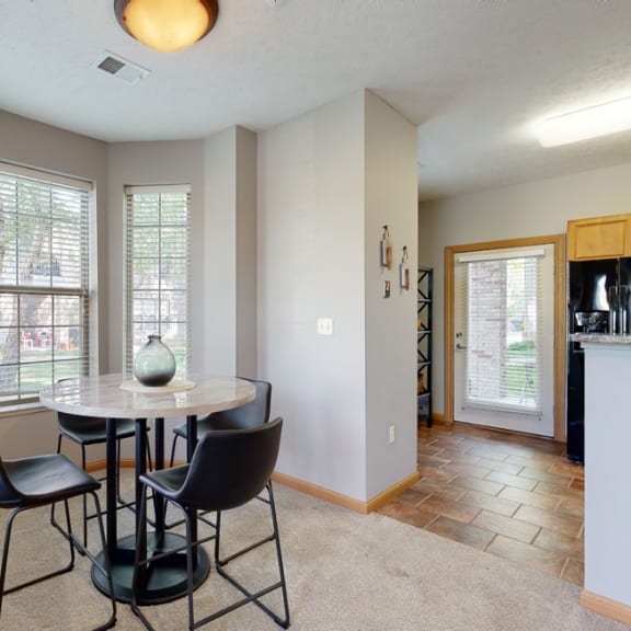 Thumbnail 5 of 19 a dining area with a table and chairs and a kitchen in the background