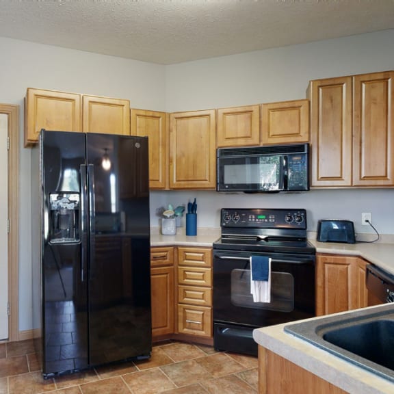 Thumbnail 7 of 19 a kitchen with wood cabinets and black appliances