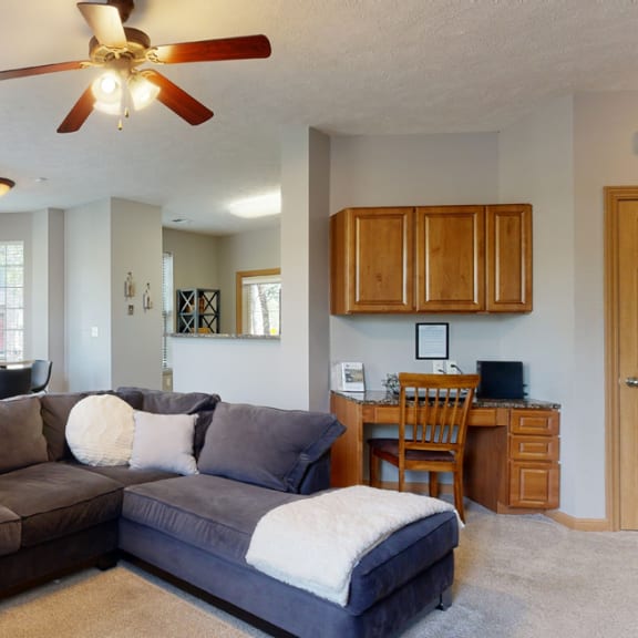 Thumbnail 4 of 19 a living room with a large sectional couch and a ceiling fan with built in desk in back