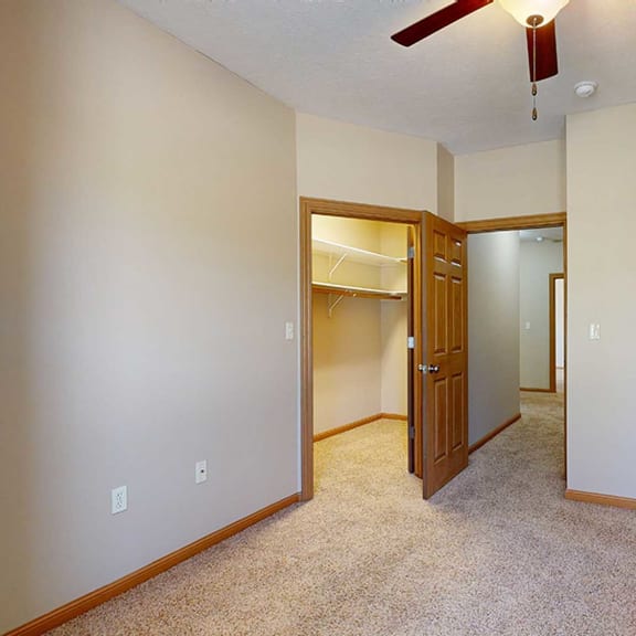Thumbnail 21 of 28 a bedroom with a ceiling fan and doors to the walk-in closet and hallway