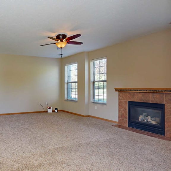 Thumbnail 13 of 28 a living room with a fireplace and a ceiling fan adjacent to a kitchen