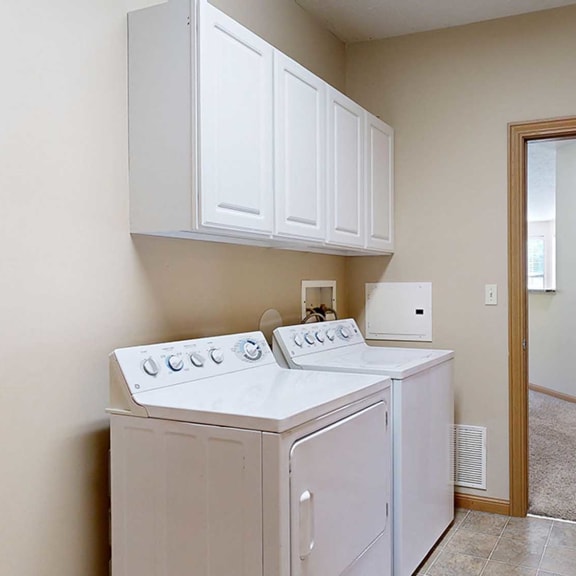 Thumbnail 26 of 28 a laundry room with a washer and dryer and a door to the hallway