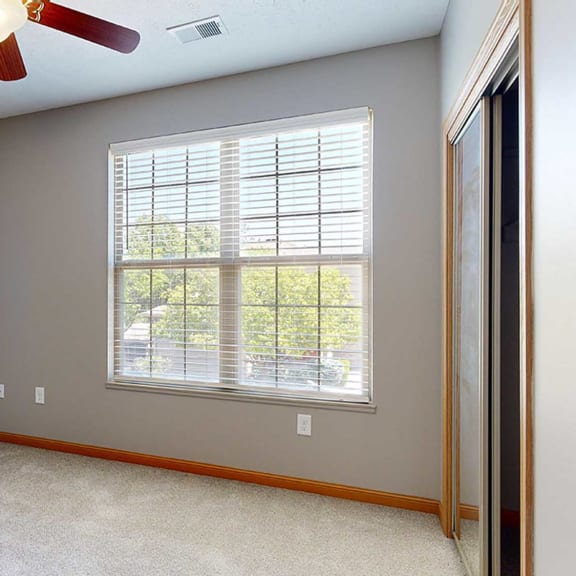 Thumbnail 22 of 24 a bedroom with a large window, a ceiling fan, and a sliding door closet
