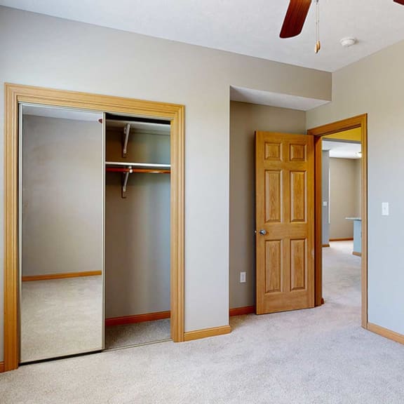 Thumbnail 21 of 24 a bedroom with a closet, large window, and ceiling fan