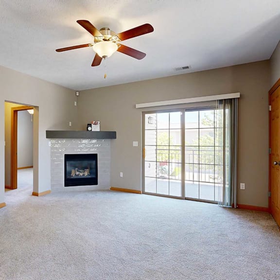 Thumbnail 10 of 24 a living room with a fireplace, sliding glass doors to a balcony, and a ceiling fan