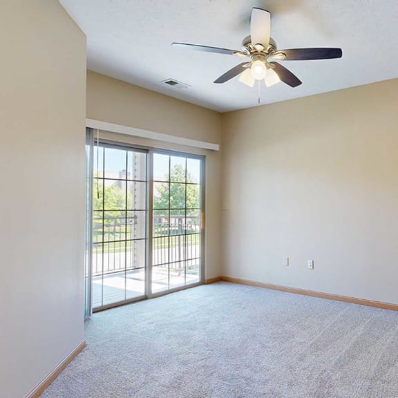 Thumbnail 15 of 32 a bedroom with a ceiling fan and sliding glass door to a balcony