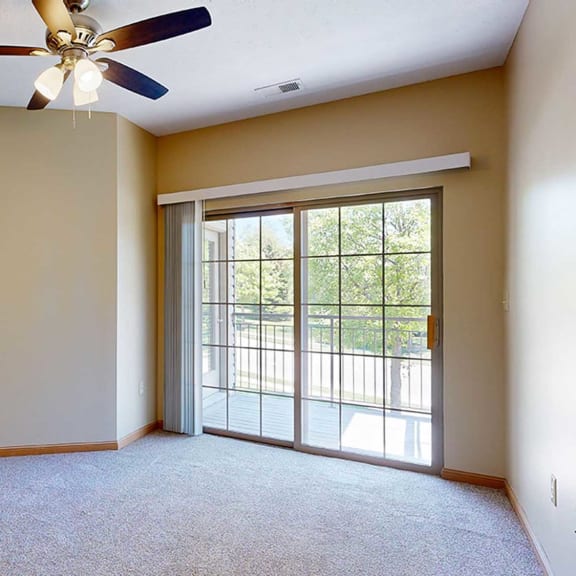 Thumbnail 16 of 32 a bedroom with a ceiling fan and sliding glass door to a balcony