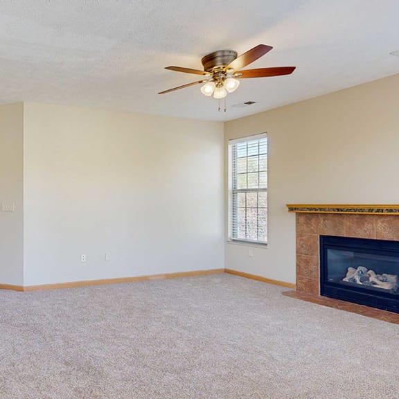 Thumbnail 14 of 32 a living room with a fireplace and a ceiling fan adjacent to a kitchen