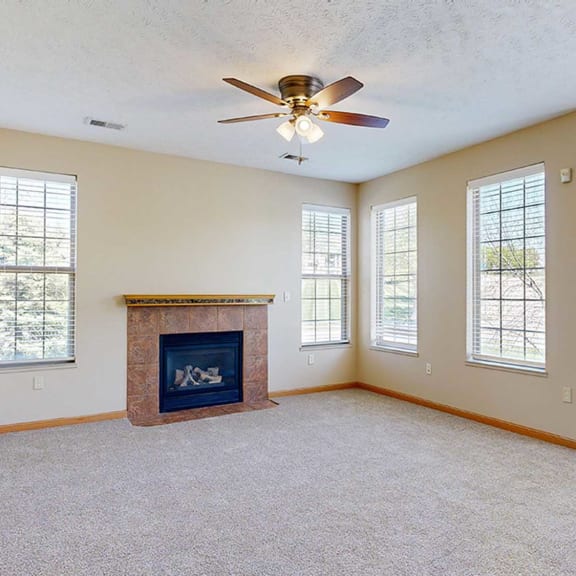 Thumbnail 4 of 32 a living room with several windows, a fireplace, and a ceiling fan