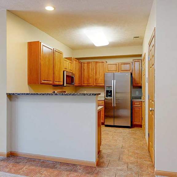 Thumbnail 6 of 31 A kitchen with a bar top counter, wooden cabinets, and stainless steel appliances.