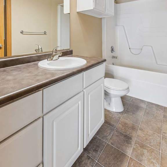 Thumbnail 30 of 31 Apartment bathroom with a white vanity, large wall mirror, overhead lighting, tile flooring, and a tub-shower combination.