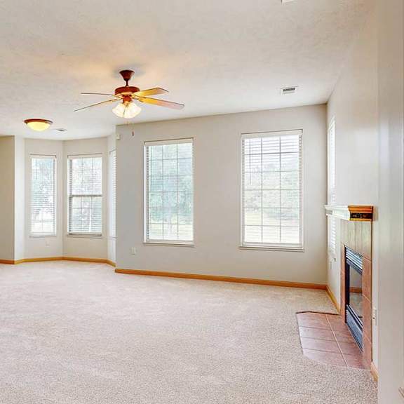 Thumbnail 10 of 39 A spacious living room with several windows, a tile fireplace, and a ceiling fan.