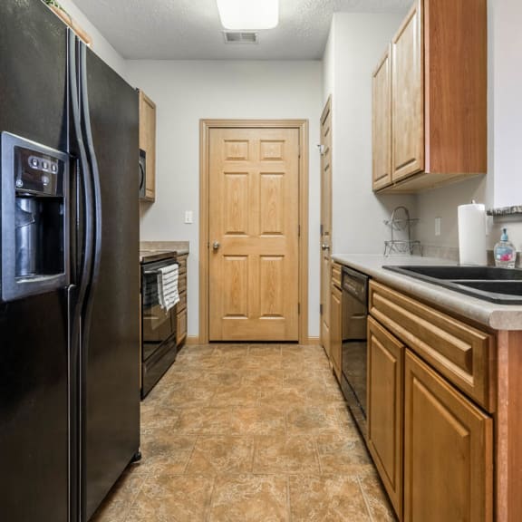 Thumbnail 2 of 12 a kitchen with a refrigerator and a sink and a door