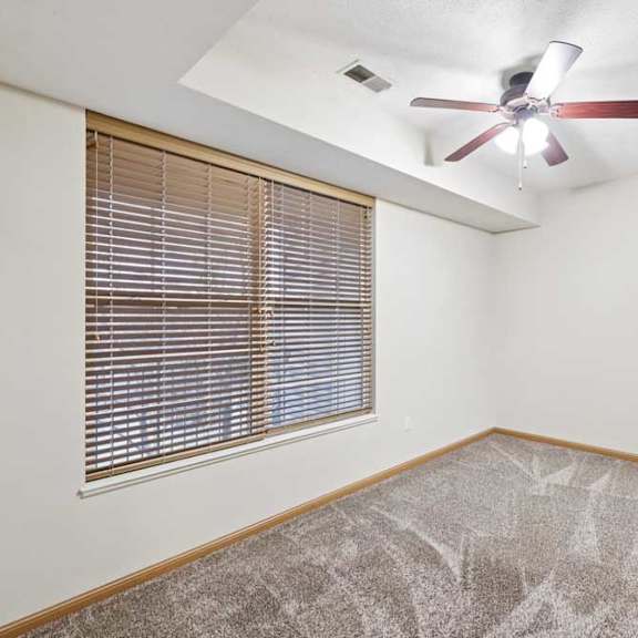 Thumbnail 14 of 23 Bedroom with large window, ceiling fan, and neutral carpet.