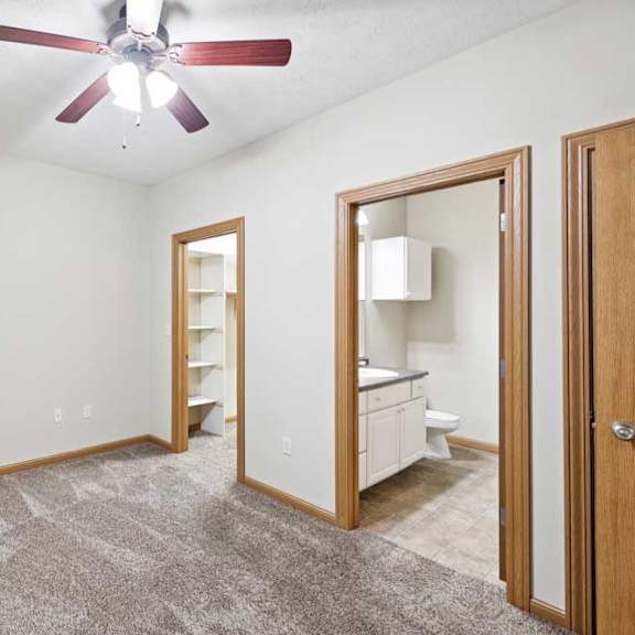 Thumbnail 16 of 23 Bedroom with ceiling fan and open access to bathroom and hallway.