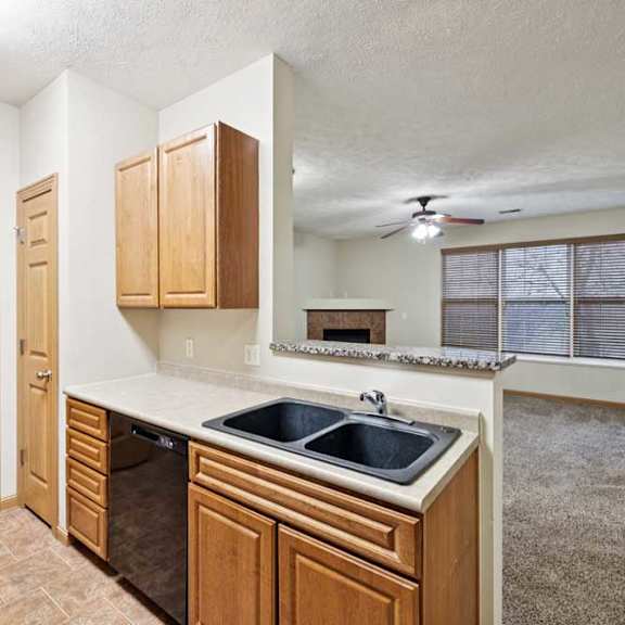 Thumbnail 3 of 23 Kitchen with natural wood cabinets, double-basin sink, laminate countertops, and breakfast bar overlooking living area.