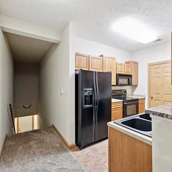 Thumbnail 4 of 23 Galley-style kitchen with black refrigerator, oven, microwave, and ample cabinet storage.