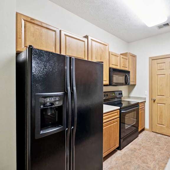 Thumbnail 5 of 23 A kitchen with a black refrigerator, microwave, oven and sink.