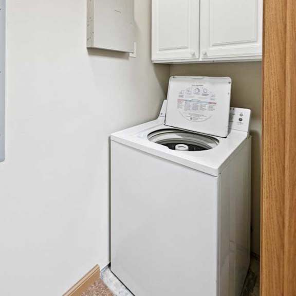 Thumbnail 8 of 23 A white washing machine in a small laundry room.