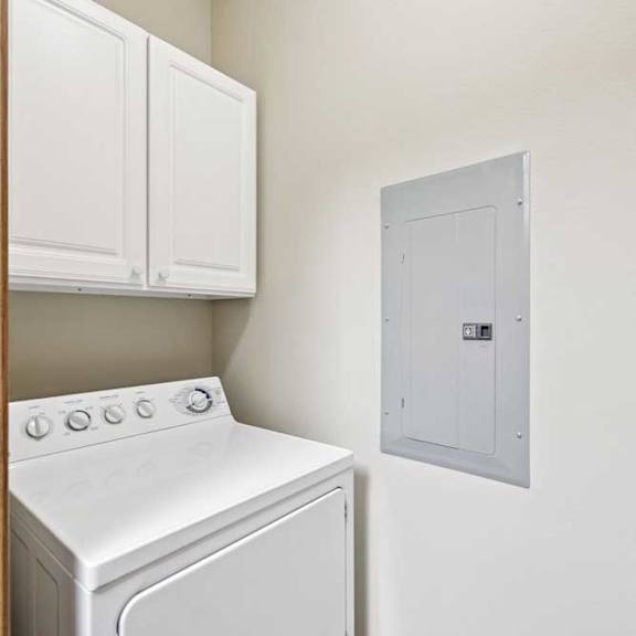 Thumbnail 7 of 23 In-unit laundry area with dryer, white upper cabinets, and tile flooring.