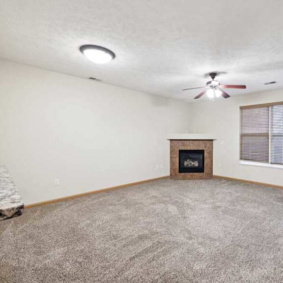 Thumbnail 10 of 23 Bright living room with large window, ceiling fan, and corner fireplace.