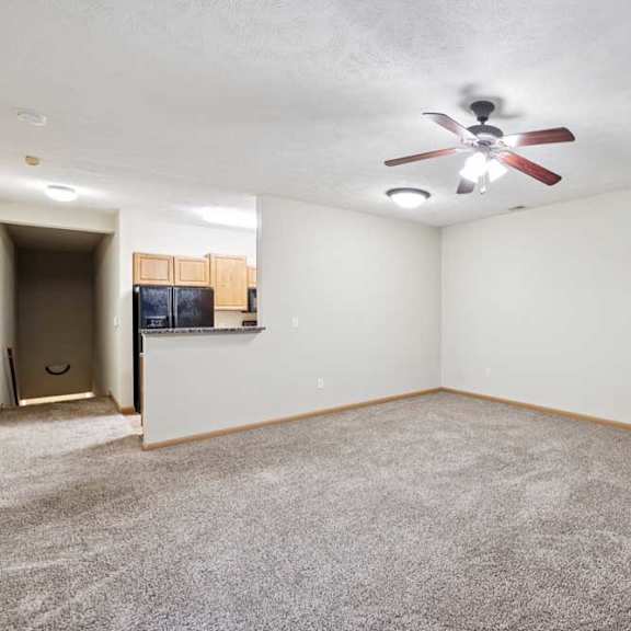 Thumbnail 13 of 23 Open living and dining area with ceiling fan, plush carpet, and fireplace with tile surround.
