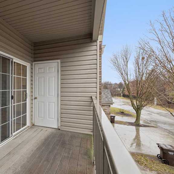 Thumbnail 7 of 19 Private balcony with sliding glass door entry, exterior storage closet, and views of the apartment community grounds.