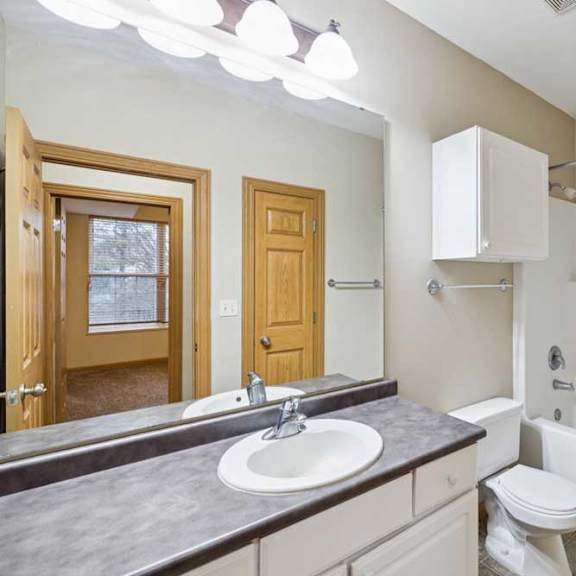 Thumbnail 19 of 19 Full bathroom with single-sink vanity, large mirror, white cabinetry, and tub-shower combo with built-in surround.