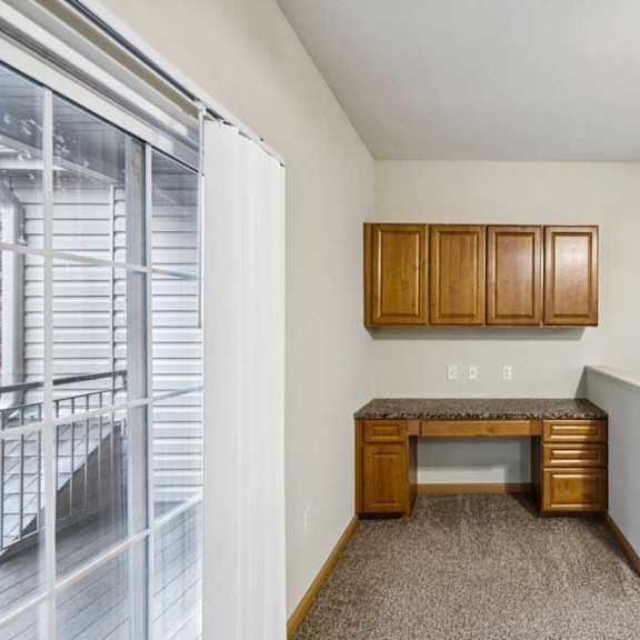 Thumbnail 5 of 19 Built-in desk area with upper cabinets and granite-look countertop, located near sliding door to the balcony.