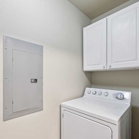Thumbnail 13 of 19 In-unit laundry area with full-size washer and dryer, plus overhead white storage cabinets.