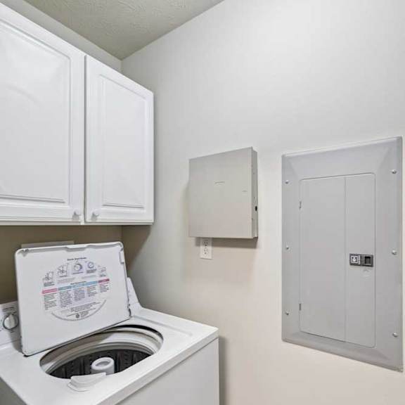 Thumbnail 14 of 19 Laundry closet with top-load washer, dryer, and adjacent electrical panel inside the apartment.