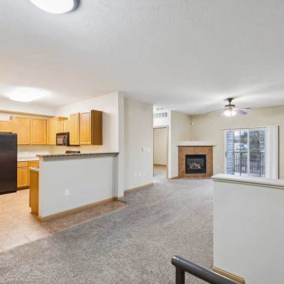 Thumbnail 2 of 19 Open-concept living and kitchen area with breakfast bar, black appliances, and sliding glass door to balcony.