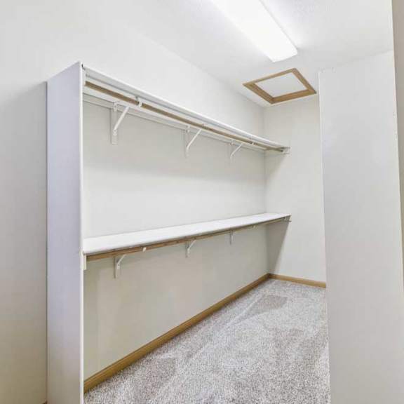 Thumbnail 16 of 19 Walk-in closet with built-in shelving, double hanging rods, and carpeted flooring for organized storage.