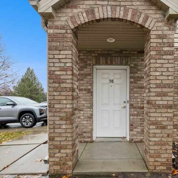 Thumbnail 3 of 19 Brick apartment exterior with covered arched entry and private front door.