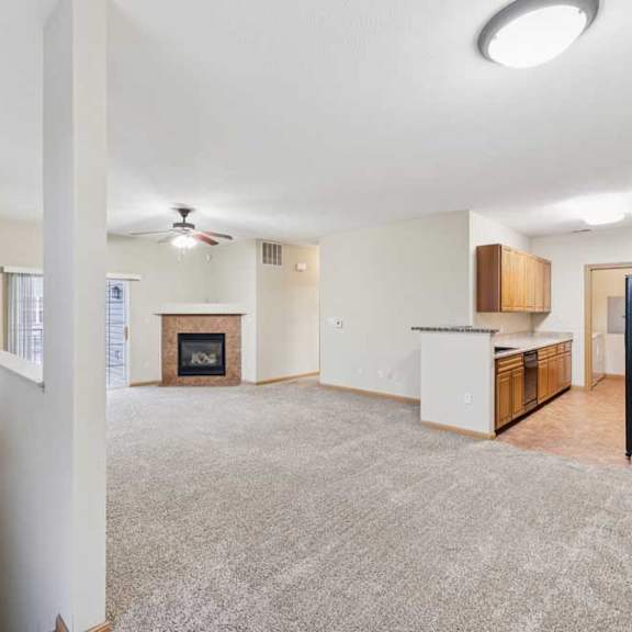 Thumbnail 4 of 19 Open-concept living area with plush carpet, fireplace with tile surround, and kitchen with breakfast bar.