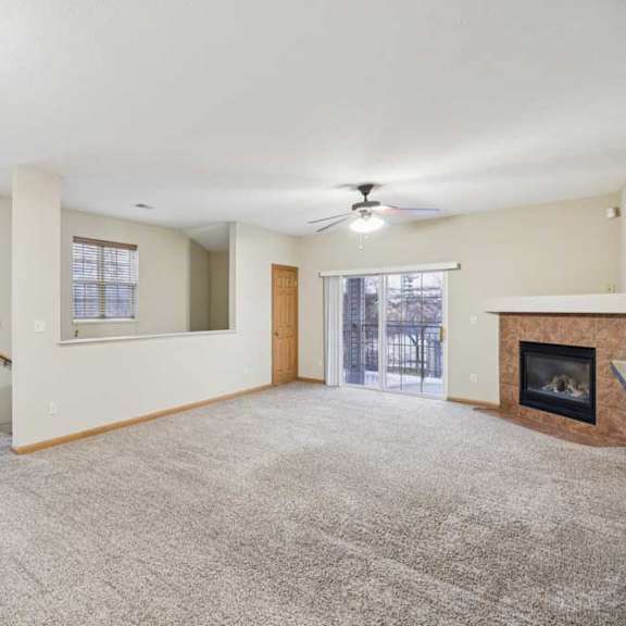 Thumbnail 11 of 19 Spacious living room with ceiling fan, sliding glass door to private balcony, and corner gas fireplace.
