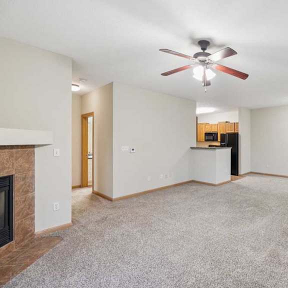 Thumbnail 13 of 19 A living room with a fireplace and a ceiling fan.